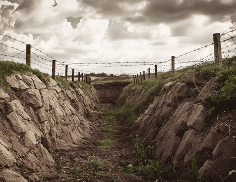 World war trench with barbed wire and cloudy sky old photography