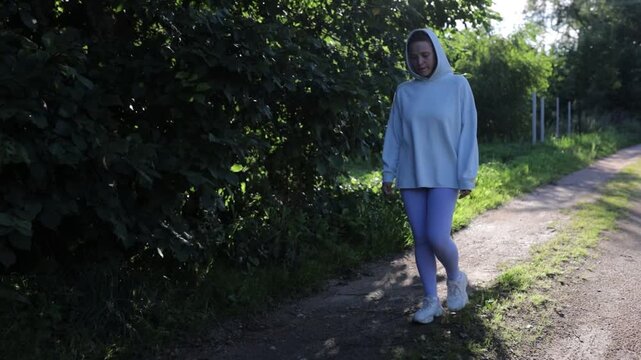 A woman in sportswear walking through a village in summer