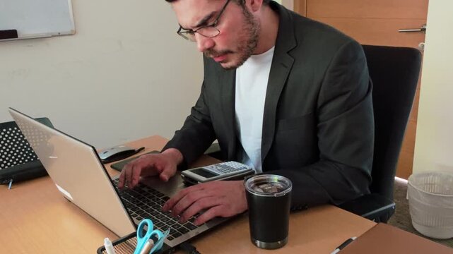 Young Man Crunching Numbers at Office Desk