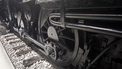 Close up of the driving wheels and mechanical rods of a black BR 41 steam locomotive. Heavy industrial machinery and vintage railway engineering details © Anna