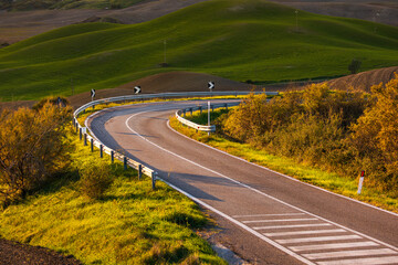 Naklejka premium Winding road curves through rolling Tuscan hills, Italy.