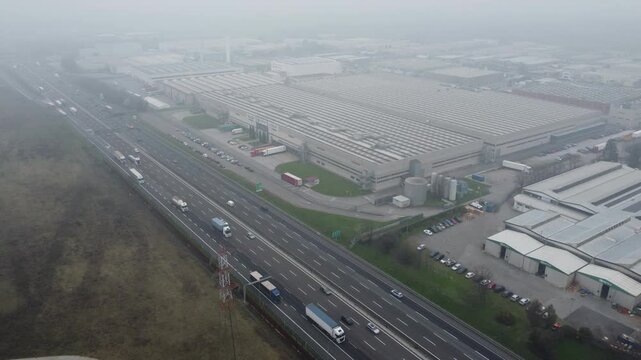Aerial view of A4 freeway in Cavenago di Brianza near Milano, Lombardia, Italy with smog, pollution, fog. Italian landscape with industrial buildings and highway traffic