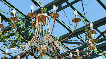 Golden chandelier hanging in green outdoor structure Moscow