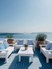 Fototapeta premium Bright white outdoor lounge overlooks the deep blue Mediterranean Sea under a clear sky in a typical Greek island setting.