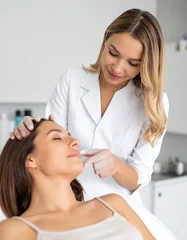 Esthetician examines a client's face in a bright salon setting before cosmetic procedure © mahadewi