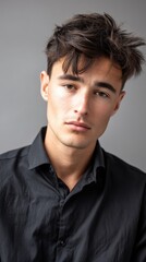 Obraz premium Headshot of a young male with tousled dark hair and a serious expression, looking directly at the camera, ideal for corporate or lifestyle imagery 