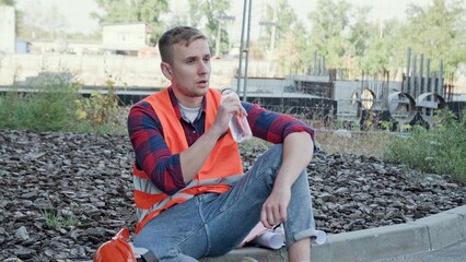Obraz premium Tired builder replenishing fluid loss during work break on site