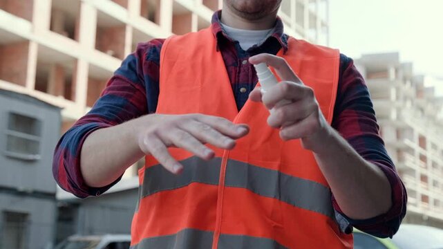 Builder disinfecting his hands on development site