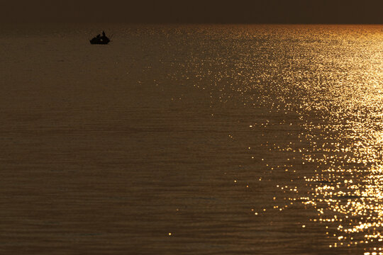 Silhouette of a fishing boat sailing at Sundarban tiger reserve during sunset, India