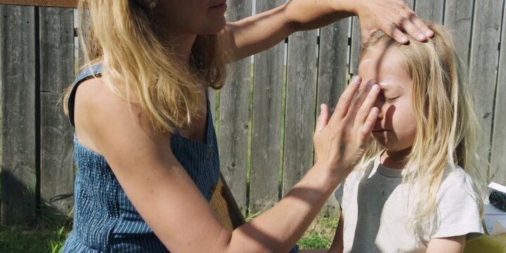 Mother applying sunscreen to her child's face outdoors