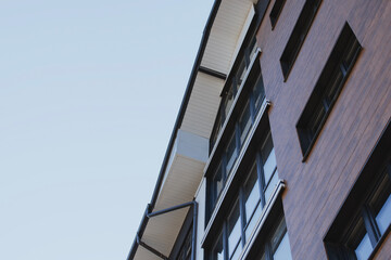 Commercial building exterior featuring horizontal dark wooden cladding panels and large black framed glass windows showcasing premium architectural design for business environments.