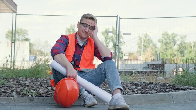 Portrait of tired architect sitting on ground