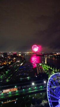 Night Drone View of La Grande Roue at Old Port Montreal with Fireworks over St. Lawrence River