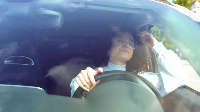 Close up of sad tired young beautiful woman sitting inside the car and waiting to drive. Traffic jam concept. Caucasian attractive female driving own vehicle. Urban life