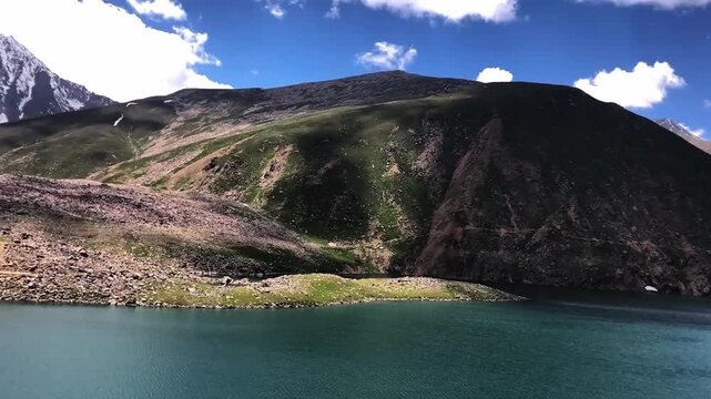 Scenic video of Lulusar Lake in Kaghan Valley, Pakistan, surrounded by lush green hills beneath a dramatic cloudy sky. Ideal for travel films, nature documentaries, and peaceful landscape footage.