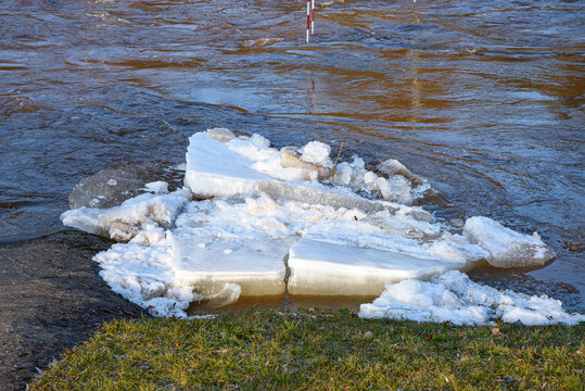 River ice breakup with monitoring gauges during spring flood, flowing water and ice jam along forest riverbank.