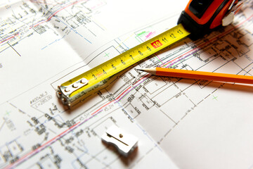 A sheet of construction drawings, a tape measure and a pencil