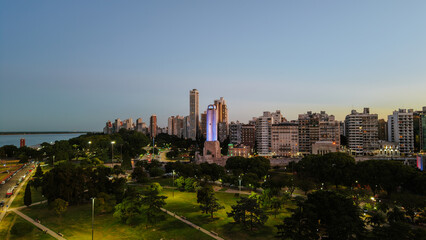 Fototapeta premium Panoramic aerial view of the National Flag Memorial in Rosario, Argentina, with the Paraná River and urban skyline at sunset