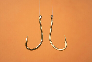 Two brass fishing hooks suspended vertically from lines