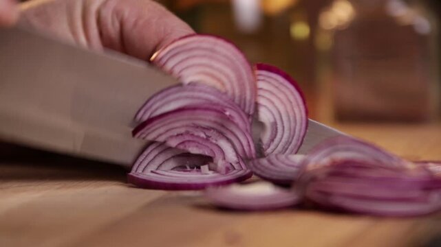 A chef cuts onions for a salad on a cutting board. Close-up.