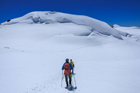 Mountaineers in rope team with crampons descending, mountain summit Parrotspitze on Monte Rosa massif and glacier panorama in Pennine Alps, Switzerland