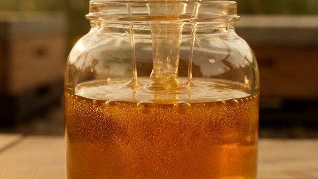 Honey flows from the comb into a jar, showcasing the essence of natural sweetness and beekeeping practices.