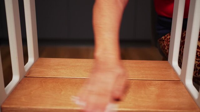 Person wipes the surface of a wooden table in a home setting in the evening