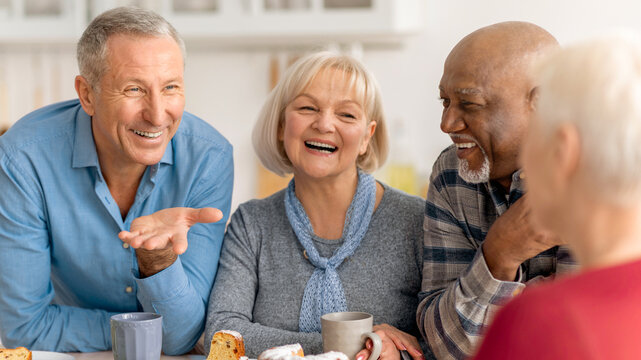 Four friends gather around a table in a kitchen, sharing laughter and stories while enjoying coffee and cake. The mood is friendly and lively as they connect and reminisce.