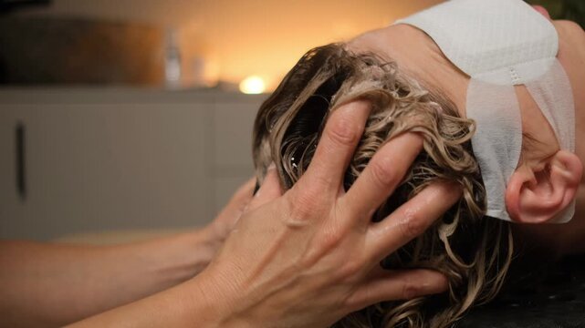 Professional hairstylist giving a relaxing head massage while washing a client's hair in a spa