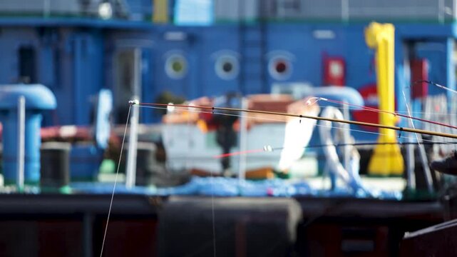 Fishing rods on a pier with a blurred industrial ship in the background, Batumi seaport.