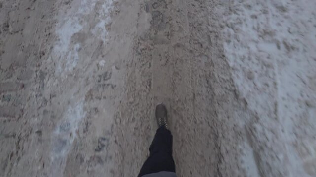 Footstep journey over frozen terrain. Visual of boot progressing over textured icy pavement amidst winter urban environment