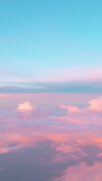 Aerial view from airplane window on ethereal beautiful sunset sky while early evening air flight through soft pink fluffy clouds with cotton candy texture. Vertical video 4K. Calming heaven background