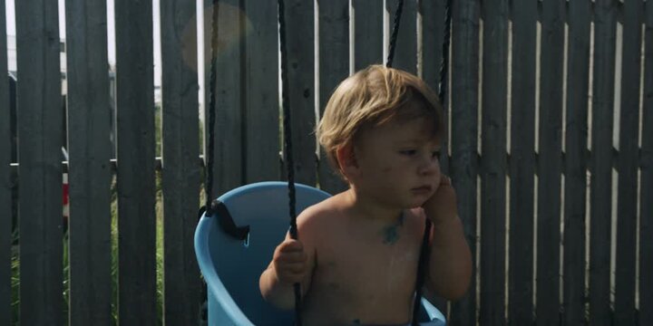 Young boy covered in paint sitting in a swing