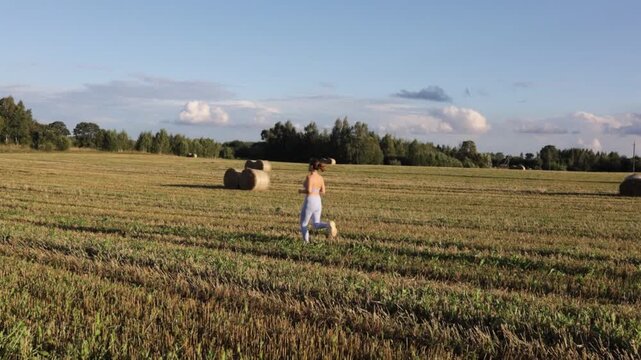 young woman jogging in a field on a sunny day in summer