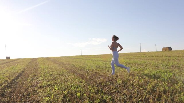 young woman jogging in a field on a sunny day in summer