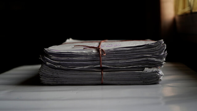 Stack of old newspapers tied with twine on wooden table in dim light