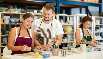 Experienced potter explains to students how to shape clay to make beautiful ceramic dishes