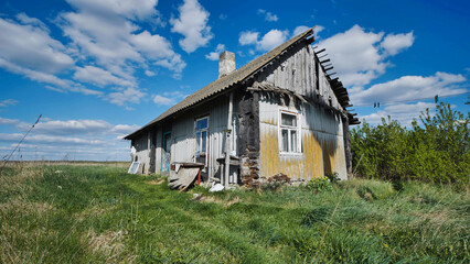 Obraz premium Old abandoned wooden house falling apart in slavic village under blue sky