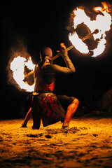 Night Beach Fire Dancer Performing Flaming Staff Show on Tropical Sand © bartsadowski