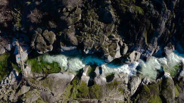 Aerial view of Los Pilones Bridge area in Garganta de los Infiernos, Spain. Exceptional river flow surging through granite formations in Jerte Valley, creating powerful whitewater and dramatic flood.