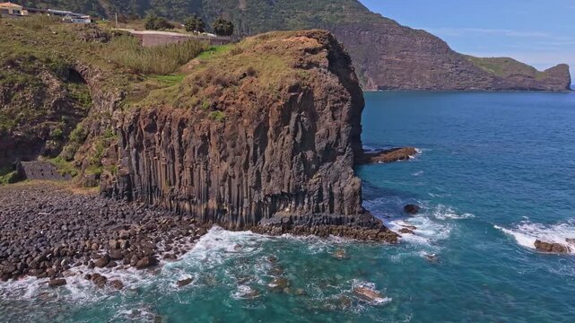 Aerial cinematic flight over Praia do Faial, drone flying above the coastline with volcanic rocks, blue ocean and Penha d'Aguia mountain view, Madeira, 4K.