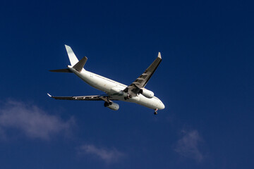 Large commercial passenger airplane flying in a clear blue sky above Iona Beach Regional Park in Vancouver Canada