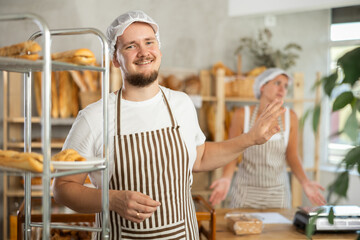 Content young man worker stands with his back to frustrated girl behind bakery counter. High quality photo © JackF