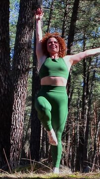 Redhead fitness model performing a one-leg jump in the forest
