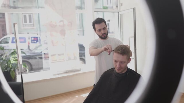 Professional hairdresser cutting customer's hair in a barbershop