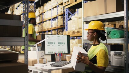 African american female verifying the shipment details on awb labels, using package tracking...