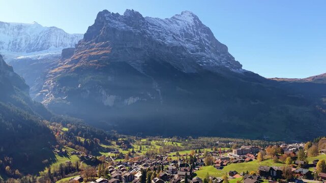 Grindelwald alpine village aerial view with traditional chalets green grass and Eiger mountain peaks in autumn. Grindelwald, Canton of Bern, Switzerland.