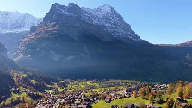 Grindelwald alpine village aerial view with traditional chalets green grass and Eiger mountain peaks in autumn. Grindelwald, Canton of Bern, Switzerland.