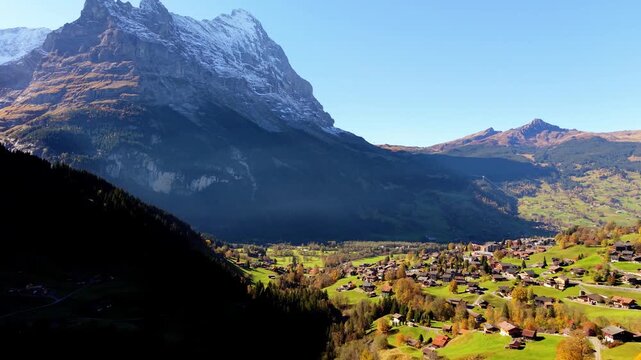Grindelwald alpine village aerial view with traditional chalets green grass and Eiger mountain peaks in autumn. Grindelwald, Canton of Bern, Switzerland.