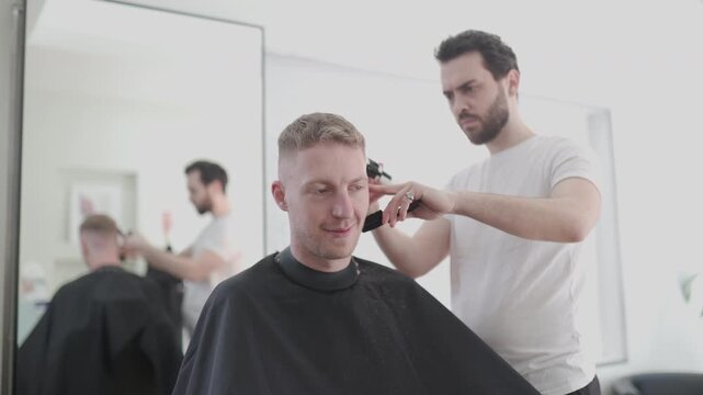 Professional barber giving a man a haircut with an electric clipper